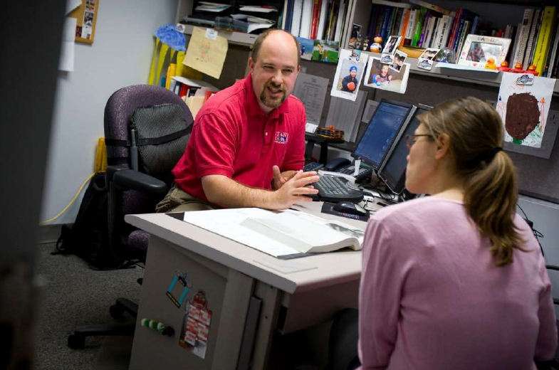 two people sit across a desk, deep in conversation